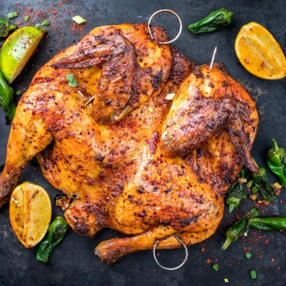 roast chicken with garnish and limes